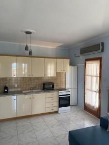 a kitchen with white cabinets and a stove top oven at Apostolis Seaside Living in Olympiada