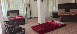 a bedroom with two beds and a chair and a mirror at Stone Man's Hotel Samana Heights in Battakundi +41 photos