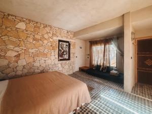 a room with a bed and a stone wall at Surfiscamp Dakhla in Dakhla