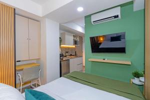 a bedroom with a green wall with a bed and a kitchen at Bit Building in Medellín