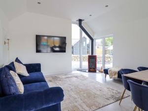 a living room with a blue couch and a fireplace at Kingfisher in Talybont