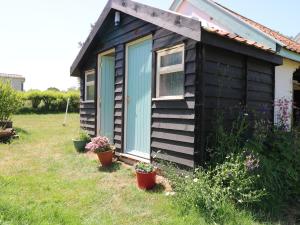 a small house with potted plants in a yard at The Bowtop Gypsy Caravan in Eye