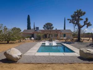 a house with a swimming pool in front of a house at Dez-Art Retreat in Yucca Valley
