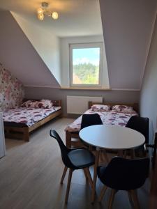a room with two beds and a table and chairs at Słoneczna Przystań in Kruklanki