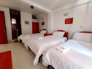 two beds in a room with white sheets at Hostal El Balcon in Ayacucho