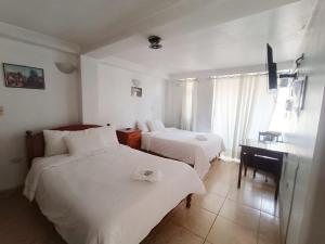 a hotel room with two beds and a desk at Hostal El Balcon in Ayacucho