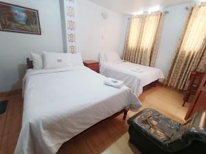 a room with two beds and a suitcase on the floor at Hostal El Balcon in Ayacucho