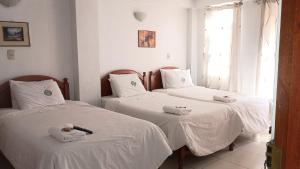 two beds in a room with white sheets at Hostal El Balcon in Ayacucho