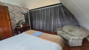 a bedroom with a bed and a chair and a window at Arch Cabins Self Catering Homes Storms River in Stormsrivier