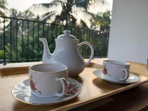 a tea pot and two cups on a tray at Parrot Paradise Negombo in Negombo