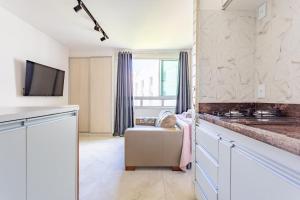 a kitchen with white cabinets and a couch in a room at Flat Sudoeste Vienna by CentoEdez in Brasília