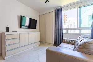 a living room with a large window and a tv at Flat Sudoeste Vienna by CentoEdez in Brasília