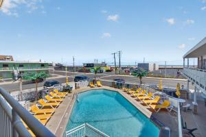 a swimming pool with yellow lounge chairs and a hotel at Starfire Motel in Wildwood