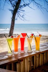 a group of different colored glasses sitting on a table at the beach at Mandurah Hotel in Kuantan