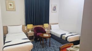 a hotel room with two beds and a chair at فندق سكب الأصيل in An Naqāʼ