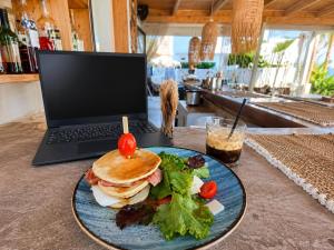 Ein Sandwich und Salat auf einem Teller neben einem Laptop in der Unterkunft Koukounari Rooms in Skala + 9 Fotos