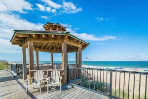 a gazebo on the beach with two chairs and the ocean at Good Trouble - Croatan Surf Club, Ocean View, Indoor and Outdoor Pool, Hot Tub, Pets Ok, YR Flex in Kill Devil Hills