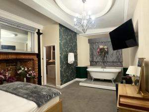 a bathroom with a tub and a bed and a television at The Scole Hotel in Scole