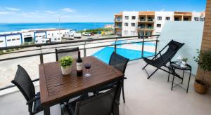 a table and chairs on a balcony with a view of the ocean at Like-Home-T1-Sun & Beach-Pools, AC in Ericeira