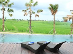 una piscina con mesa y sillas junto a palmeras en Kampung Canggu, en Canggu