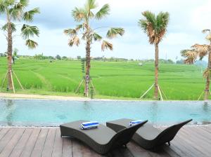 einen Pool mit einem Tisch und Stühlen neben Palmen in der Unterkunft Kampung Canggu in Canggu