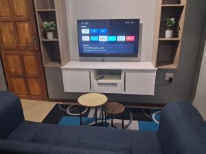 a living room with a tv and a blue couch at Trendy Tranquility in Secunda