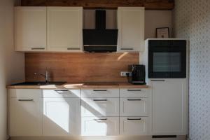 a kitchen with white cabinets and a black microwave at Ferienhaus am Dillbach in Hagen