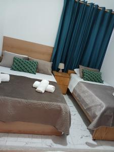 two beds in a bedroom with blue curtains at Guest House Nino's in Çorovodë