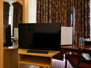 a flat screen tv sitting on top of a table at Aron Guest House in Ealing