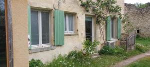 an old building with green shutters and a window at Gîte des petits givrés in Entrains-sur-Nohain