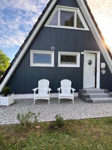 two white chairs on a patio in front of a house at Glückshaus in Brodersby