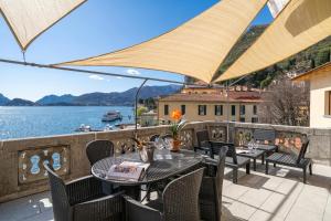 a patio with tables and chairs and a view of the water at Menaggio Tosca Apartments in Menaggio