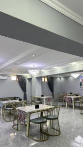 a dining room with tables and chairs and chandeliers at Hotel Imam Azam in Samarkand