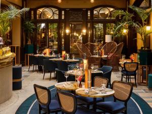a restaurant with tables and chairs and windows at l'Echiquier Opéra Hotel Paris - MGallery Collection in Paris