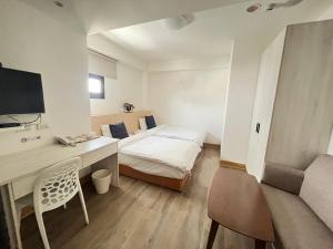a small room with a bed and a desk with a computer at Hotel Huru House in Taichung