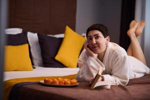 a woman laying on a bed with a plate of food at REGINA Bed&Wine in Varna City