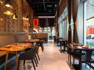 a restaurant with wooden tables and chairs and windows at ibis Dubai One Central in Dubai