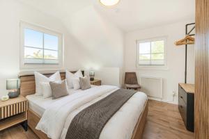 a white bedroom with a large bed and two windows at Ferienwohnung Strandliebe in Koserow