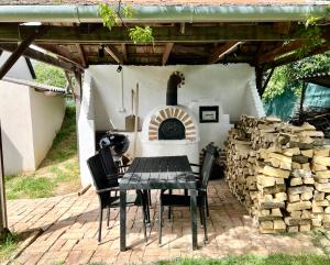 a table and chairs on a patio with a fireplace at Zselic Kuckó by Mártika in Szigetvár