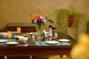 a table with plates and a vase of flowers on it at Hostal Mallqui in Cusco