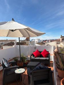 a patio with chairs and an umbrella on a roof at La Vieja Botica in Canillas de Aceituno