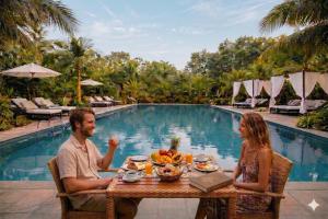 a man and woman sitting at a table in front of a pool at Hidden Valley Eco Retreat Trang An in Ninh Binh
