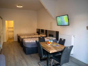 a room with three beds and a table with chairs at Race & Rest Apartments in Baar