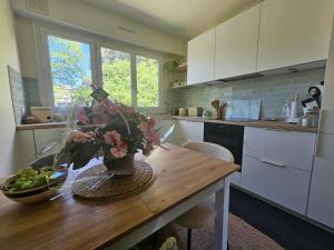 a kitchen with a wooden table with a vase of flowers at Jasmin Doux in Poitiers