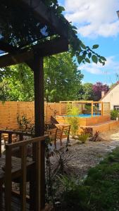 a wooden pergola with a bench in a yard at La coconing in Vierzon