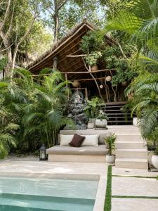 a couch sitting in front of a house with a pool at Ikal Bungalows Tulum in Tulum