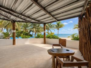 an outdoor patio with a table and chairs and the ocean at Arenika Beachfront Villa & Rooms in Puerto Morelos
