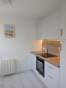 a kitchen with white cabinets and a wooden counter top at Studio cosy - terrasse privative - lit queen size in Berck-sur-Mer