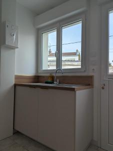 a kitchen with a sink and two windows at Studio cosy - terrasse privative - lit queen size in Berck-sur-Mer