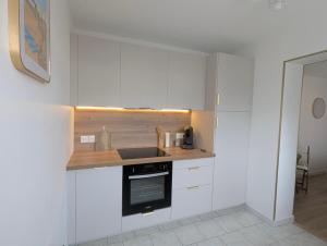 a kitchen with white cabinets and a counter top at Studio cosy - terrasse privative - lit queen size in Berck-sur-Mer +8 photos